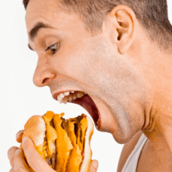 “스트레스로 인한 폭식 장면 – 햄버거를 한입에 먹는 남성의 모습”