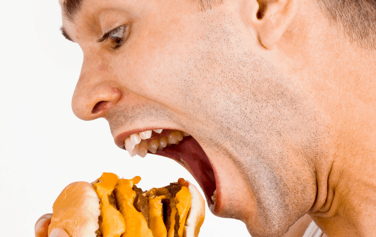 “스트레스로 인한 폭식 장면 – 햄버거를 한입에 먹는 남성의 모습”